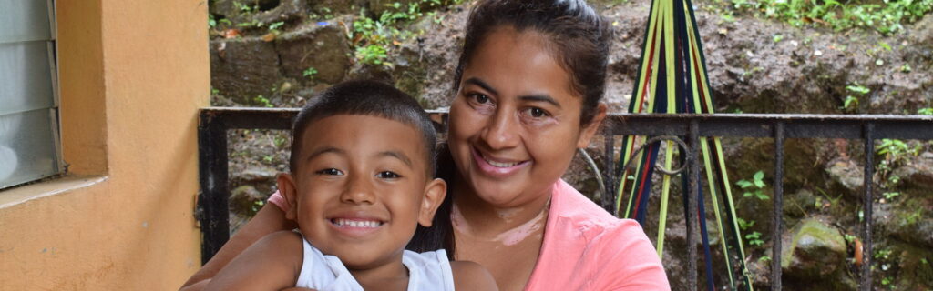 A mother and child smiling on a house porch