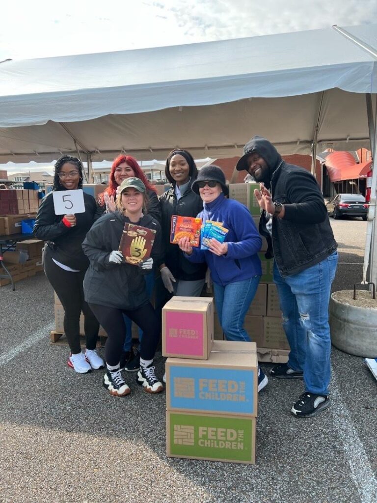 A group of volunteers posing around boxes at an event