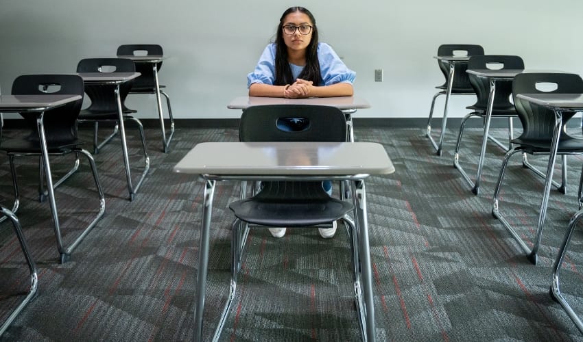 A child sitting alone in a classroom at a desk