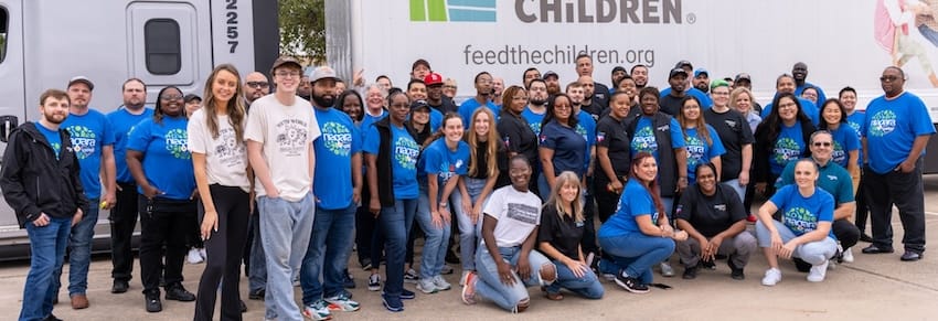 A group of volunteers in front of a semi truck at an event