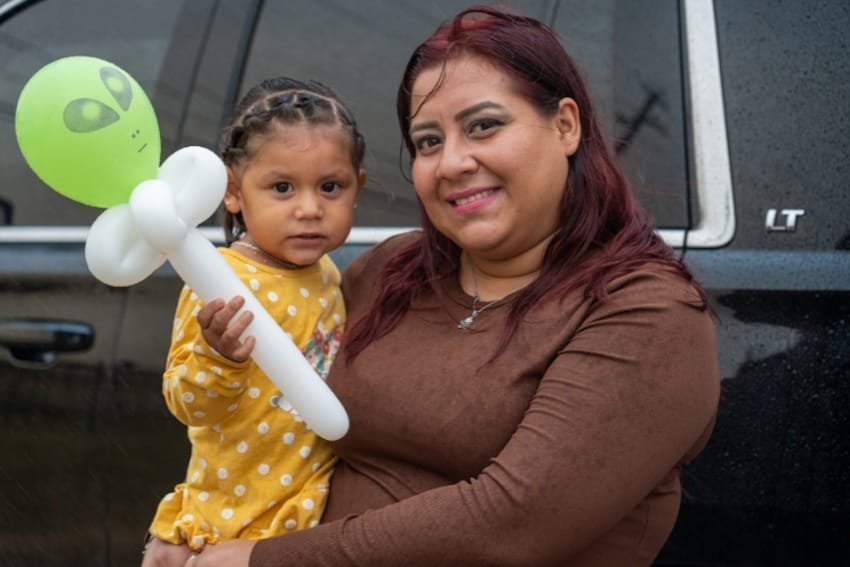 A mother and daughter smiling next to a car