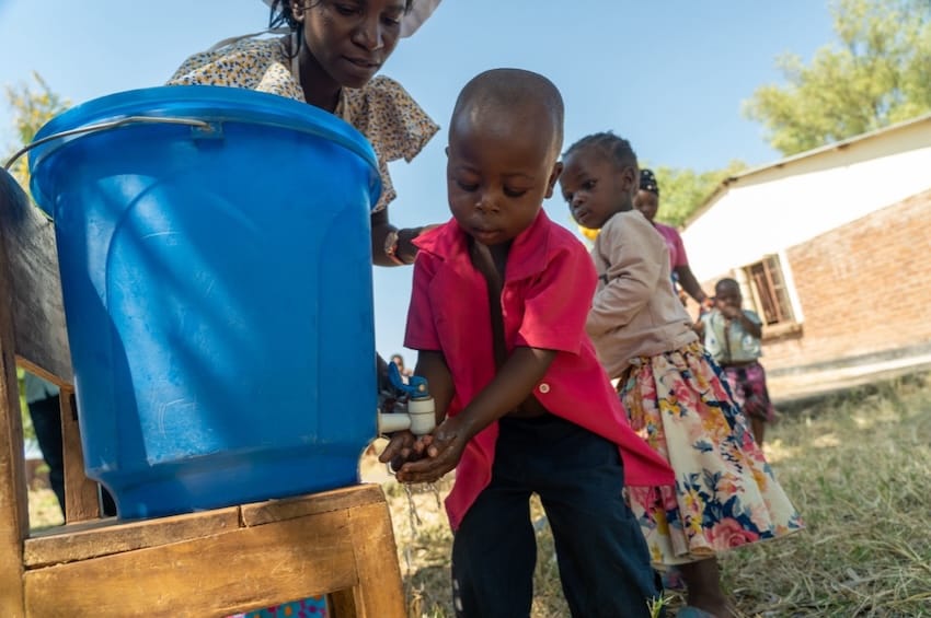 A group of children with a water bucket outdoors