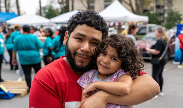 A man and his daughter hugging outdoors at an event