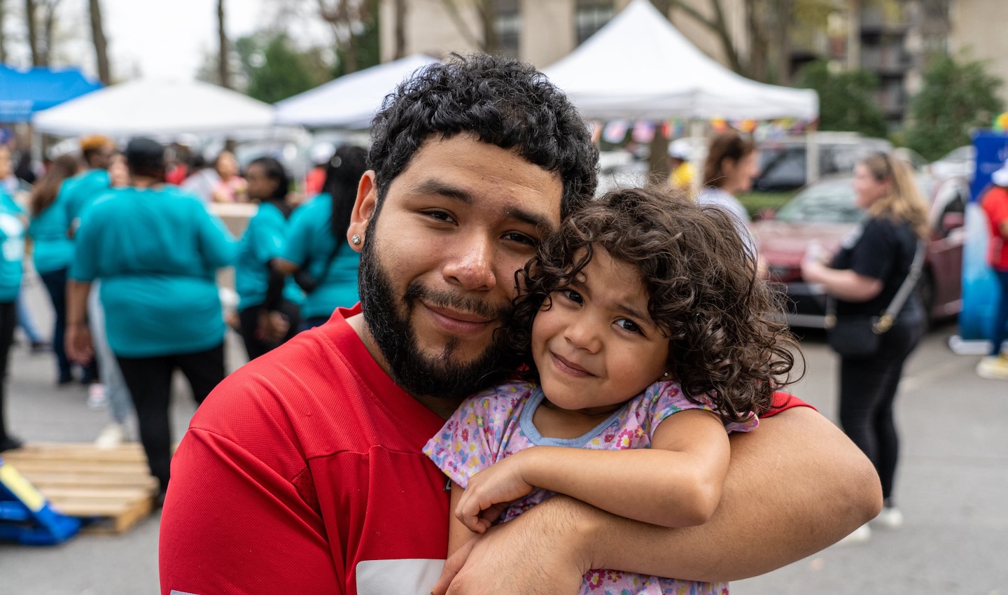 A man and his daughter hugging outdoors at an event