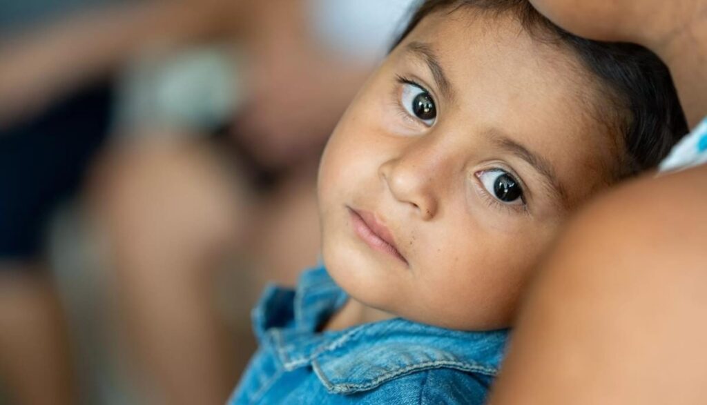 Un niño apoyado en un adulto