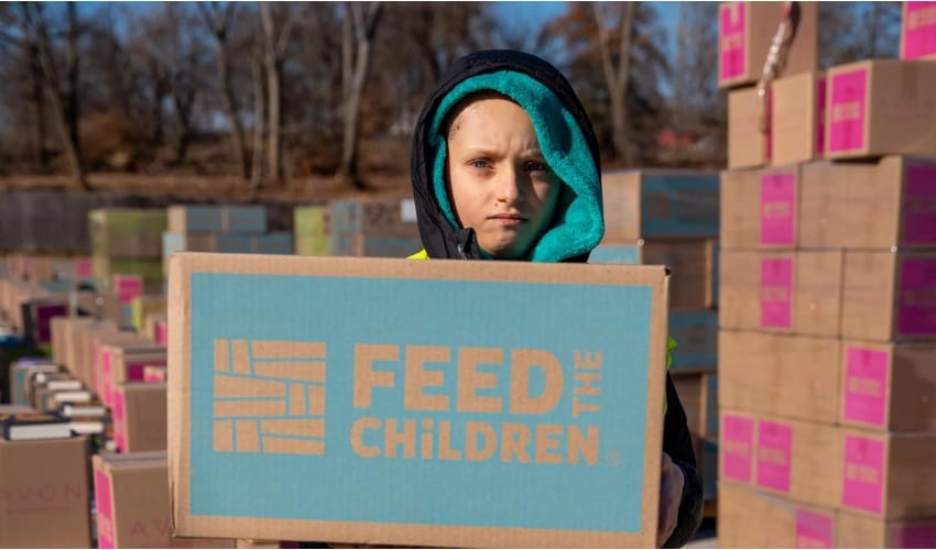 A child holding a box outdoors at an event