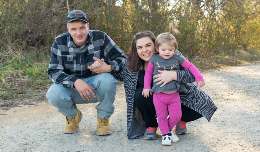 A mother and father with their daughter outdoors on a driveway