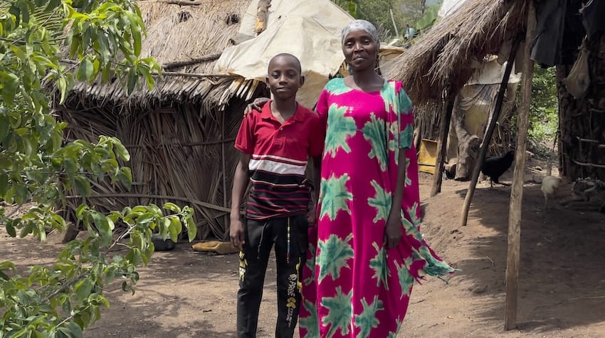 A mother and son standing in a village in Africa