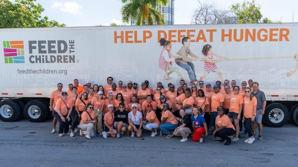 A group of volunteers taking a photo together in front of a Feed the Children semi.