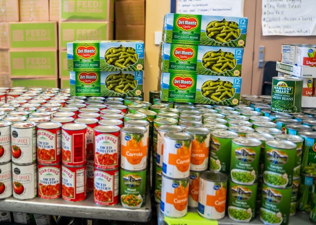 A pile of cans stacked on a table in front of boxes.