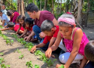 A group of children tending to a garden outdoors.