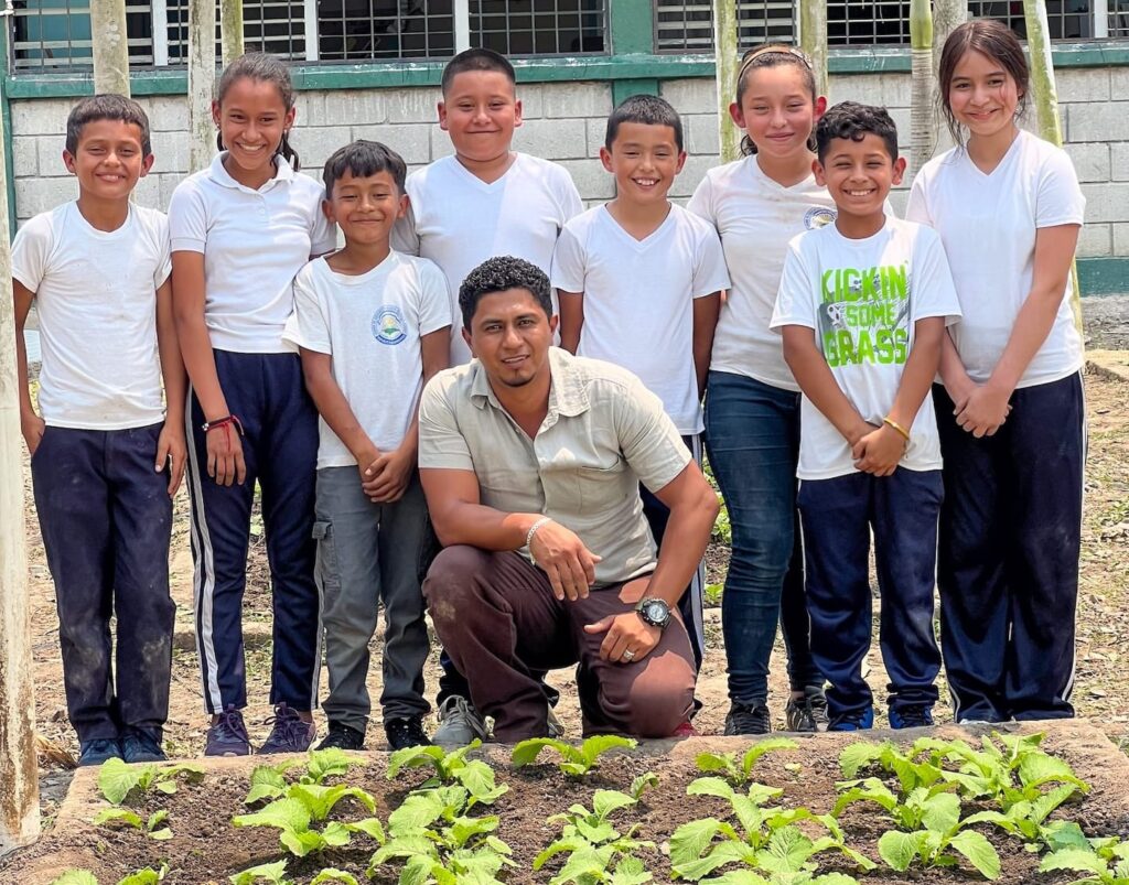 A group of students standing together in front of a garden.