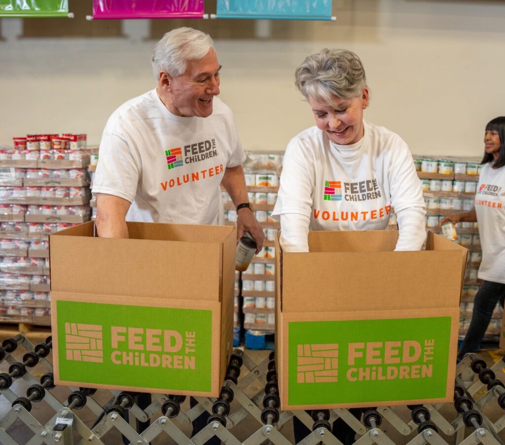 Two volunteers filling boxes with food.