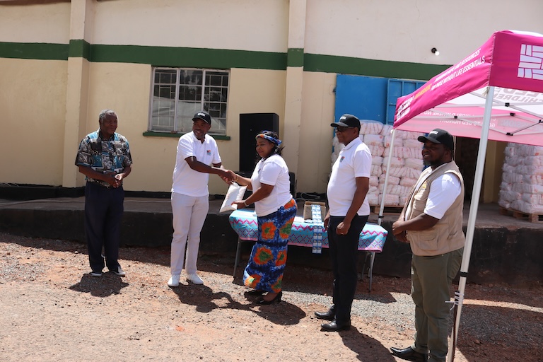 A group of people outdoors near a tent and supplies.