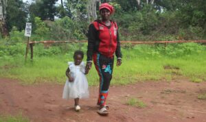 Catherine and Ackness walking in the dirt in front of the woods.