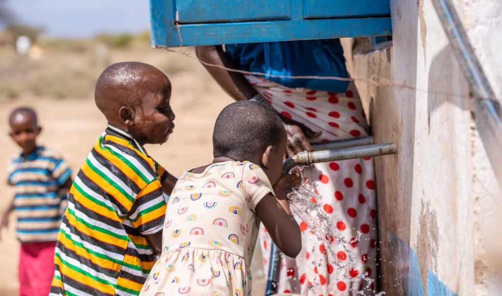Children in Kenya drinking water from a water spout.