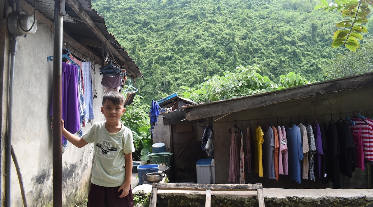 Jeecob standing next to a pole outside his house.