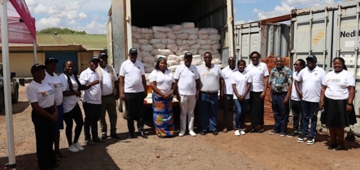 A group of people standing in front of a truck and containers of supplies.