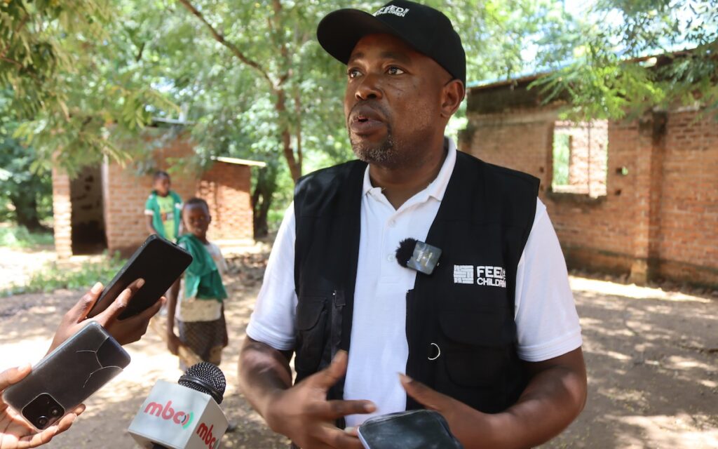 A man standing outdoors while speaking in an interview.