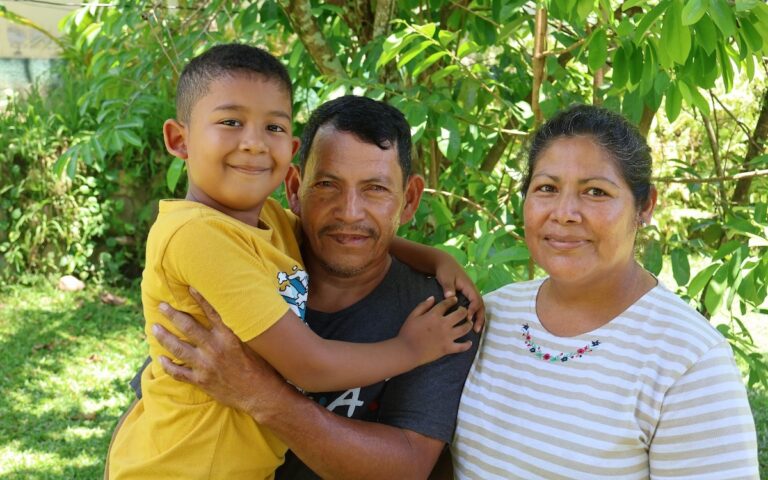 Blanca and her husband and son sitting outdoors.