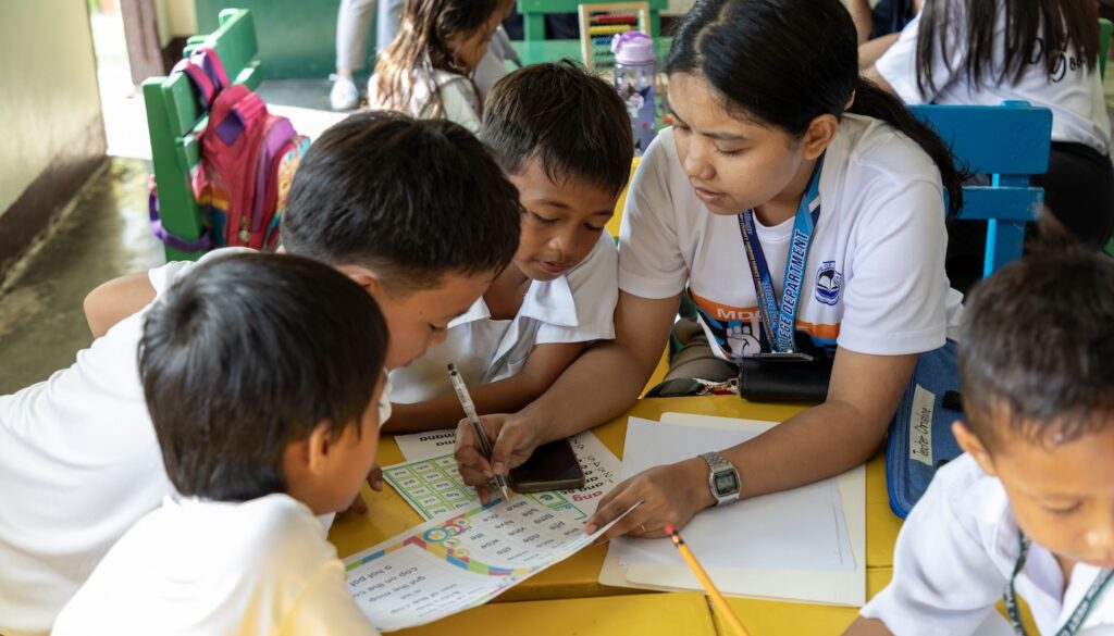 Children completing school work at a table together.