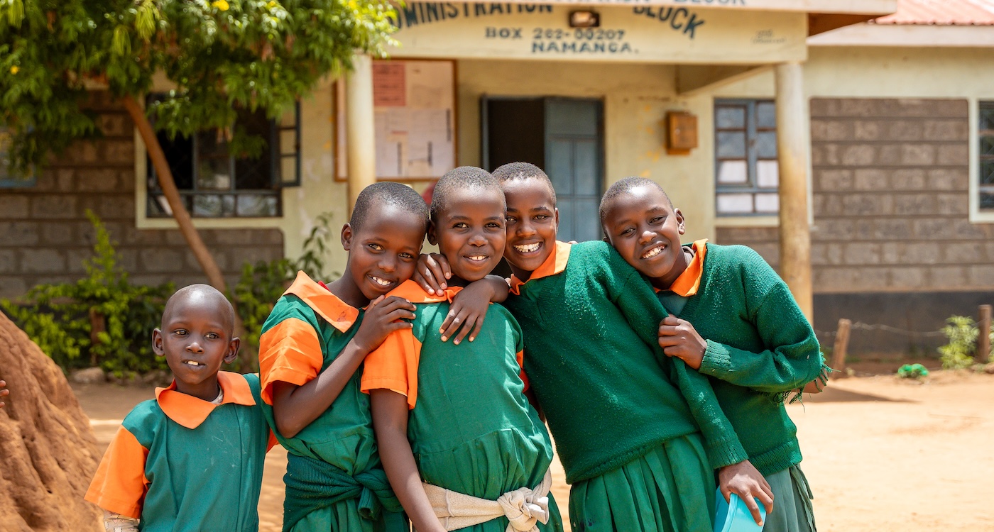 Children standing together in uniforms outside a school.