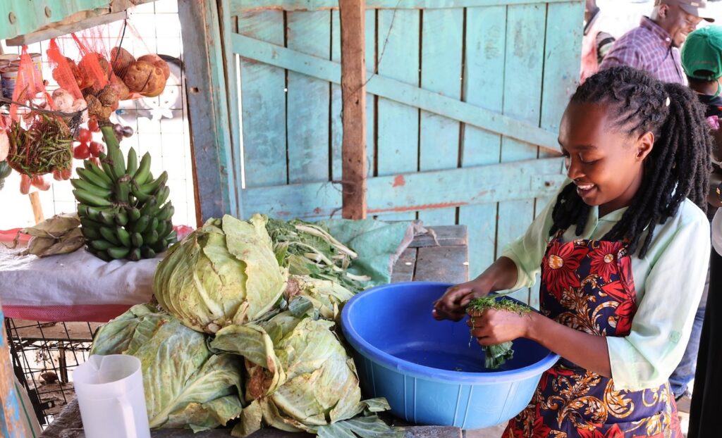 Joan preparing vegetables in a bowl in her outdoor shop.