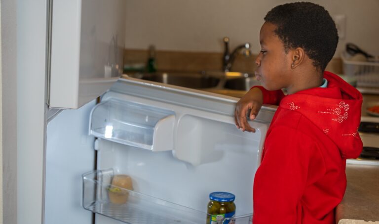 A child looking through a refrigerator for food.