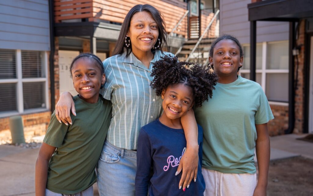 Jade and her three children standing out front of her house.
