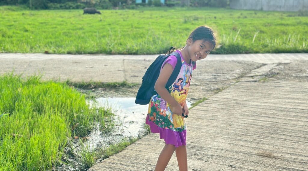Khianna wearing a backpack while smilling on a walking path.